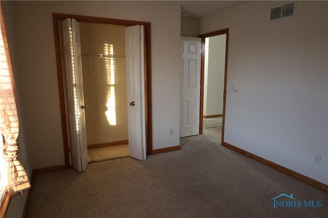 unfurnished bedroom featuring light carpet and a closet