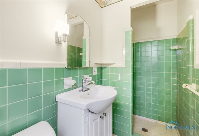 bathroom with vanity, toilet, tile walls, and tiled shower