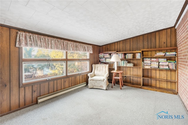 sitting room featuring carpet, wooden walls, brick wall, and a baseboard heating unit