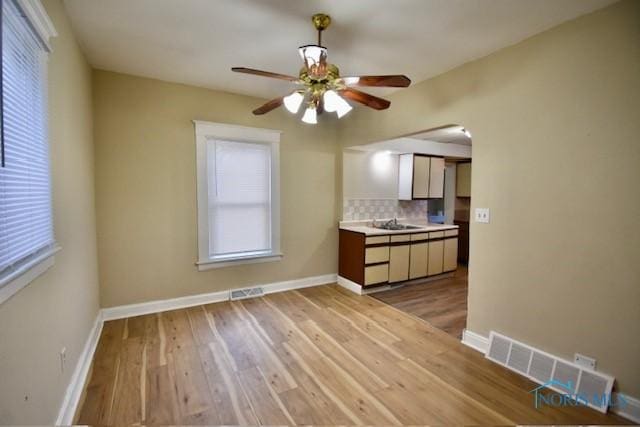 interior space with sink, backsplash, ceiling fan, and light hardwood / wood-style floors