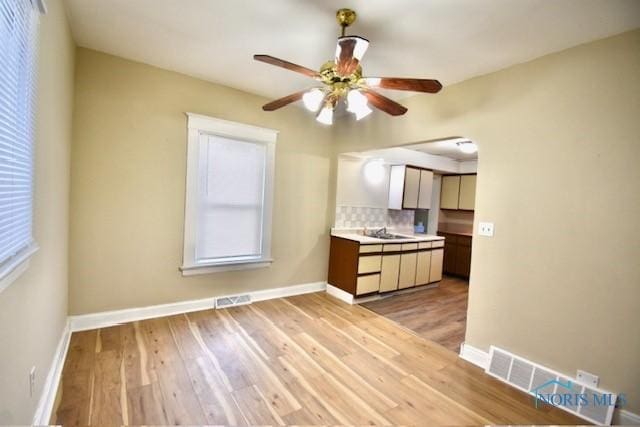 kitchen featuring backsplash, ceiling fan, and light hardwood / wood-style flooring