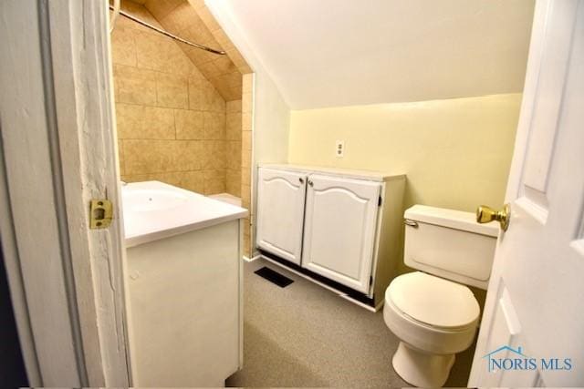 bathroom featuring toilet, vanity, and lofted ceiling