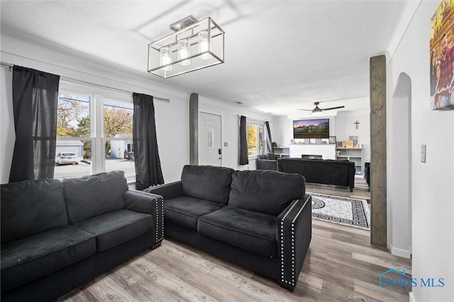 living room with ceiling fan, hardwood / wood-style floors, a stone fireplace, and a healthy amount of sunlight