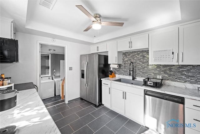 kitchen featuring sink, white cabinetry, washer and dryer, and appliances with stainless steel finishes