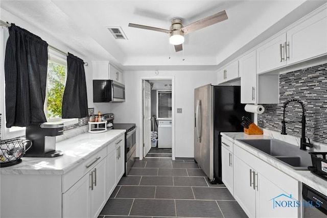 kitchen with sink, white cabinetry, backsplash, and stainless steel appliances