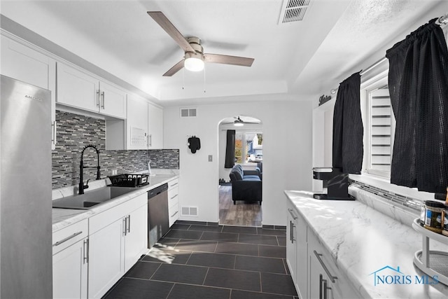 kitchen with appliances with stainless steel finishes, white cabinetry, tasteful backsplash, sink, and ceiling fan