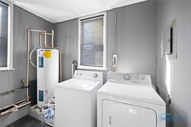 laundry area featuring independent washer and dryer, electric panel, water heater, and dark tile patterned floors