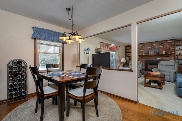 dining room with a textured ceiling, a fireplace, and wood-type flooring