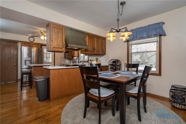 dining room featuring hardwood / wood-style flooring, ceiling fan with notable chandelier, and a textured ceiling