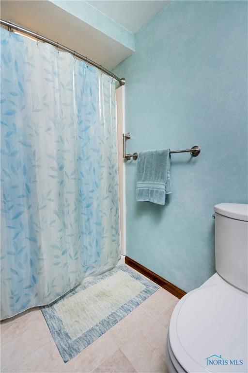 bathroom with tile patterned floors, toilet, and a shower with shower curtain