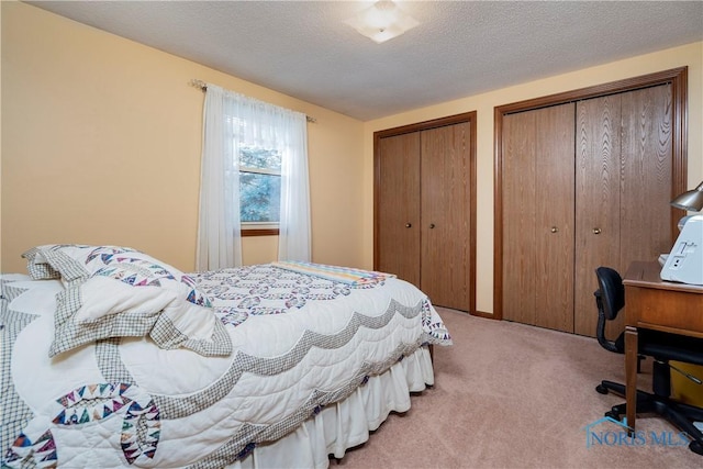 bedroom featuring multiple closets, a textured ceiling, and carpet