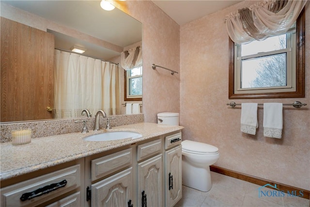 bathroom featuring plenty of natural light, toilet, tile patterned flooring, and vanity