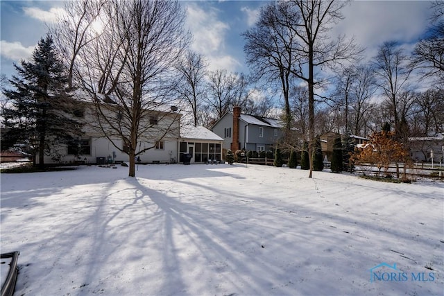 yard layered in snow with a sunroom