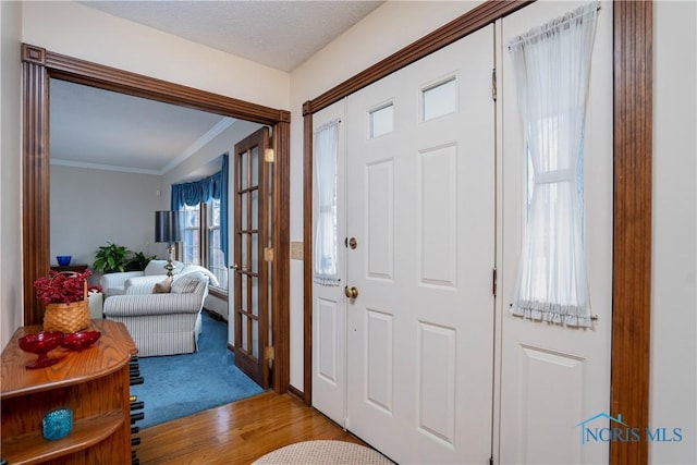 entryway with light hardwood / wood-style flooring and crown molding