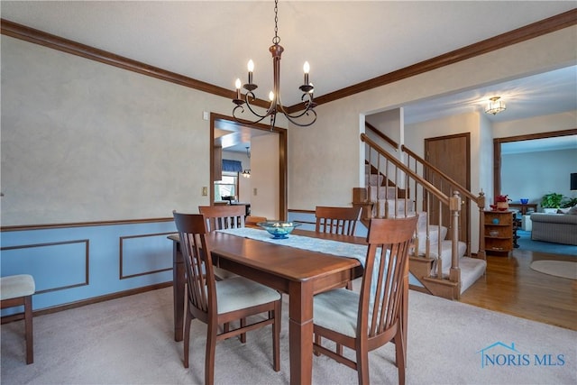 carpeted dining space with a chandelier and ornamental molding