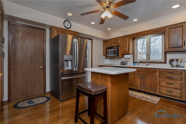 kitchen featuring dark hardwood / wood-style flooring, sink, a kitchen bar, a kitchen island, and stainless steel appliances