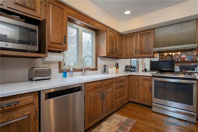 kitchen featuring sink, premium range hood, light wood-type flooring, and stainless steel appliances