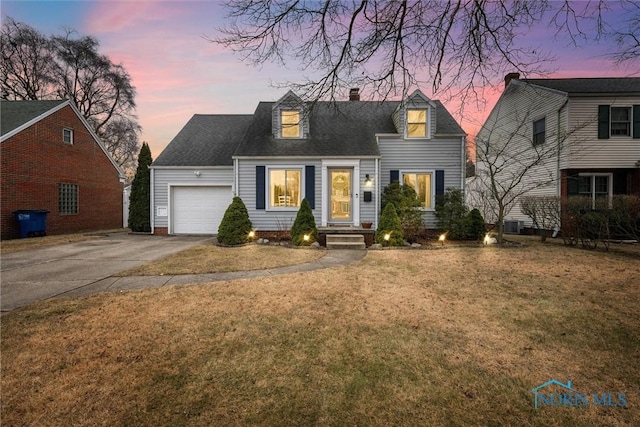 cape cod house featuring a garage and a lawn