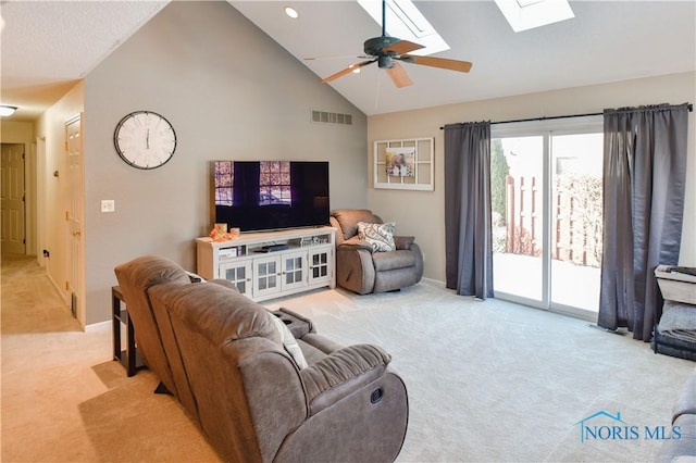 carpeted living room with ceiling fan, high vaulted ceiling, and a skylight