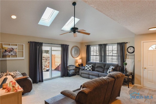 carpeted living room featuring a textured ceiling, vaulted ceiling with skylight, and ceiling fan