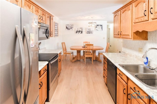 kitchen with appliances with stainless steel finishes, tasteful backsplash, sink, light wood-type flooring, and pendant lighting