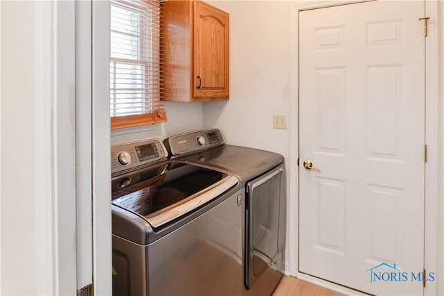 laundry room featuring separate washer and dryer and cabinets