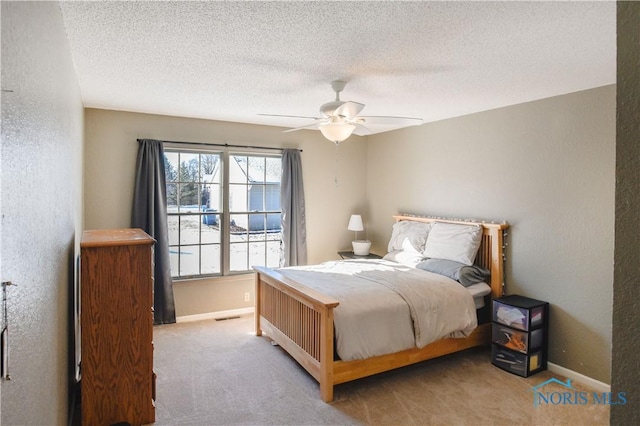 carpeted bedroom featuring ceiling fan and a textured ceiling