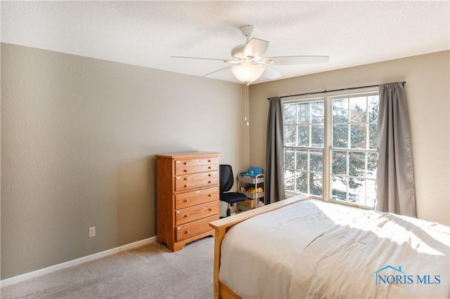 bedroom with ceiling fan, light colored carpet, and a textured ceiling