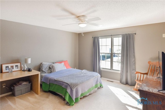 carpeted bedroom featuring ceiling fan and a textured ceiling