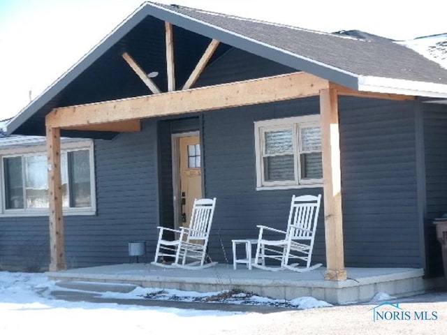 snow covered property entrance featuring covered porch