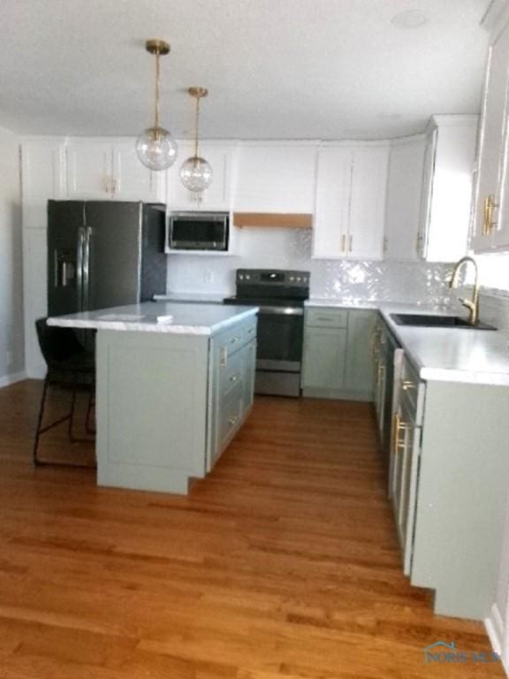 kitchen with decorative light fixtures, sink, white cabinets, and stainless steel appliances