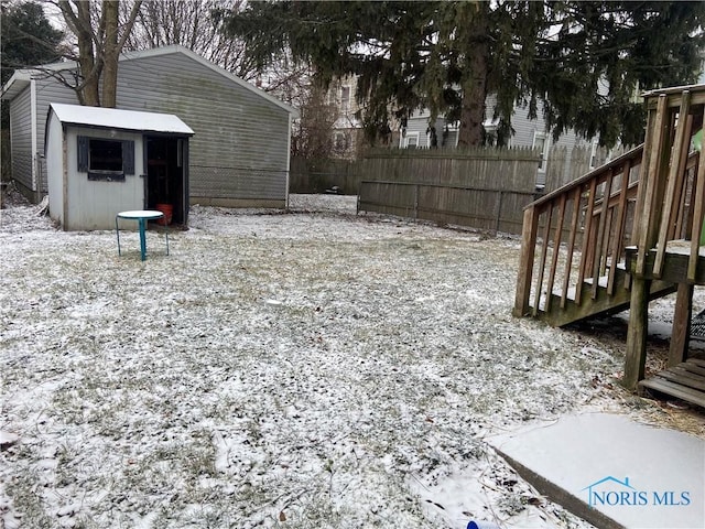 snowy yard featuring a storage shed