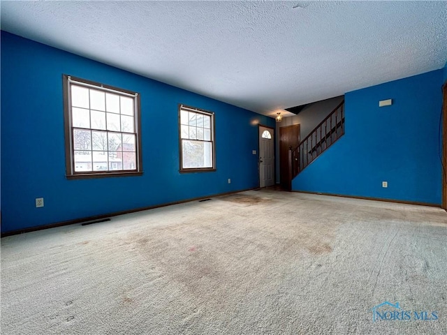 unfurnished living room featuring carpet and a textured ceiling