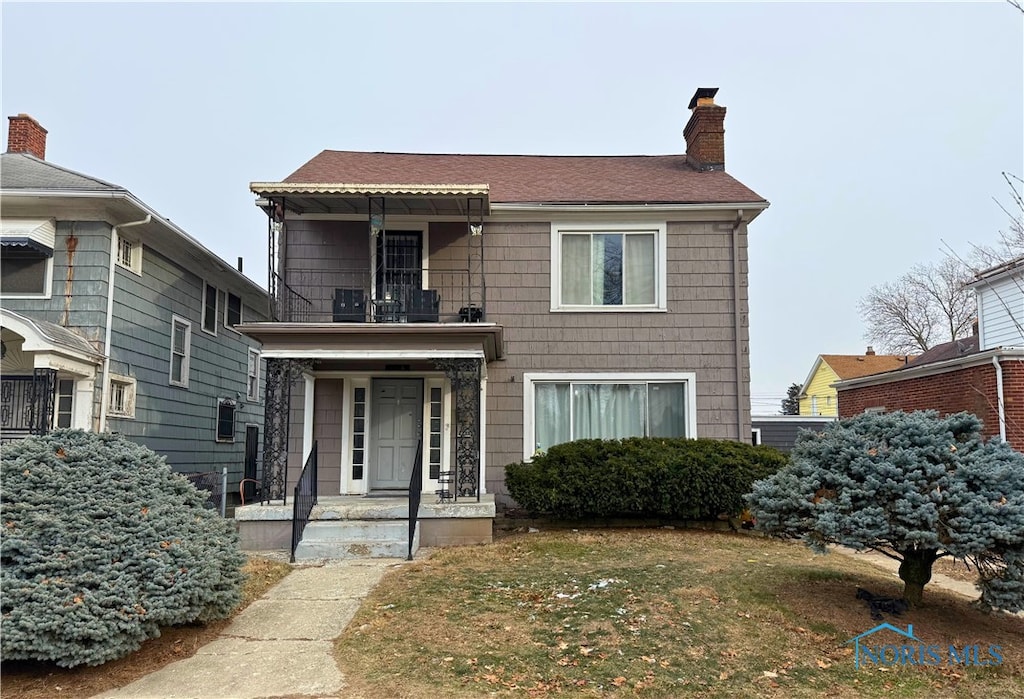 view of front of property featuring a front yard and a balcony