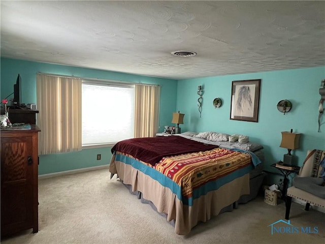 bedroom with light carpet and a textured ceiling