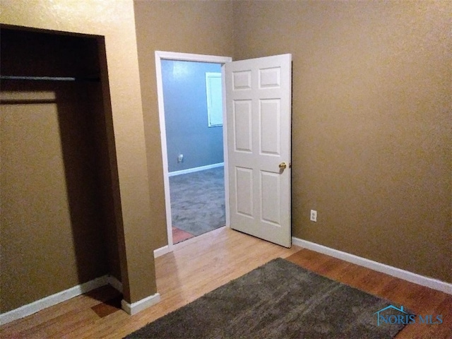 unfurnished bedroom with hardwood / wood-style floors and a closet