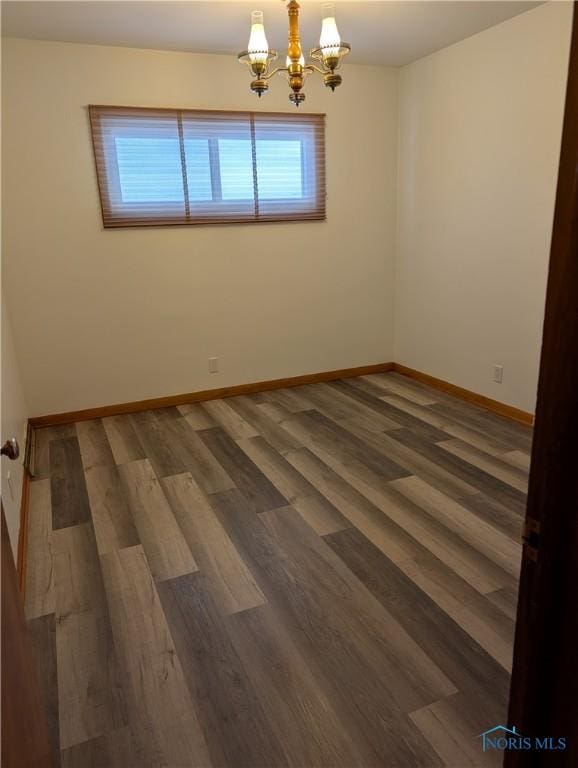 empty room with an inviting chandelier and dark hardwood / wood-style flooring