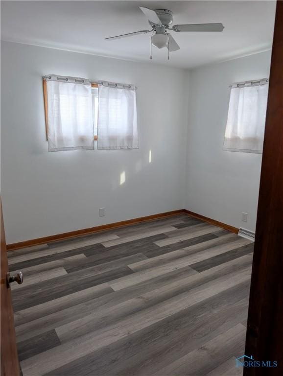 unfurnished room featuring dark wood-type flooring and ceiling fan