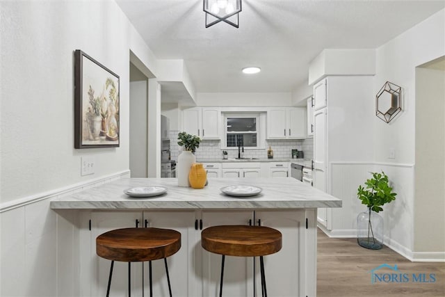 kitchen with a breakfast bar, sink, white cabinets, and decorative backsplash