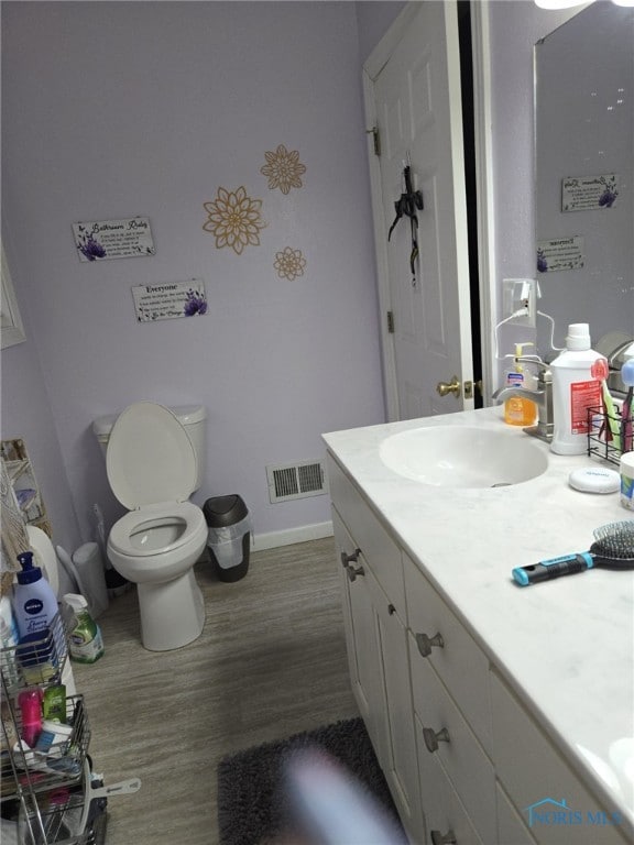 bathroom with hardwood / wood-style flooring, vanity, and toilet