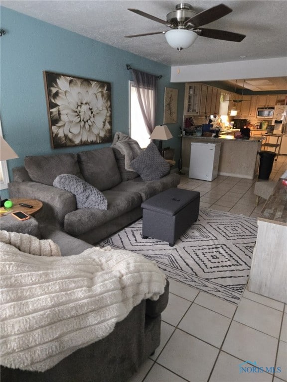 tiled living room featuring a textured ceiling and ceiling fan