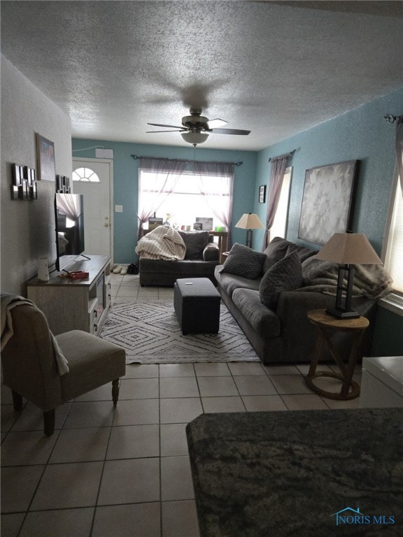 living room with ceiling fan, tile patterned floors, and a textured ceiling