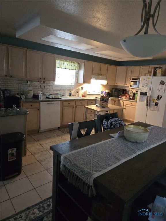 kitchen featuring light brown cabinetry, sink, light tile patterned floors, white appliances, and a textured ceiling