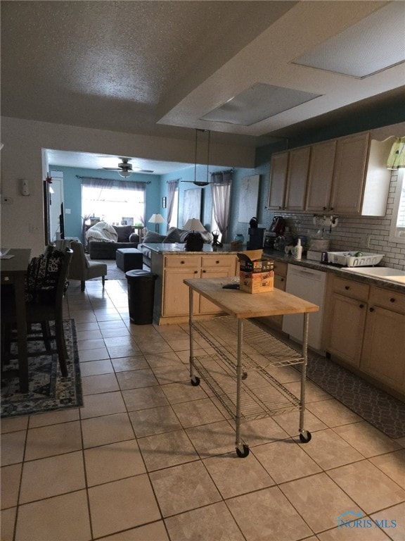 kitchen with light tile patterned flooring, decorative light fixtures, dishwashing machine, decorative backsplash, and light brown cabinets