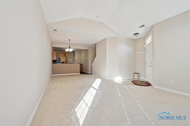 unfurnished living room featuring light carpet, a notable chandelier, and vaulted ceiling