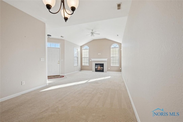 unfurnished living room with lofted ceiling, ceiling fan with notable chandelier, and light colored carpet