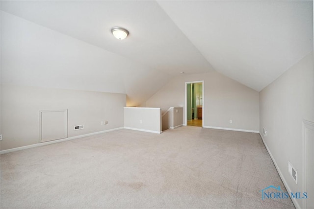 additional living space featuring light colored carpet and vaulted ceiling