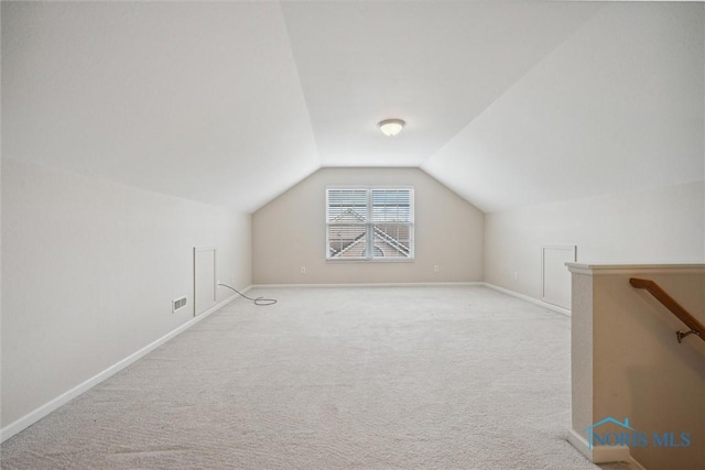 additional living space featuring vaulted ceiling and light colored carpet