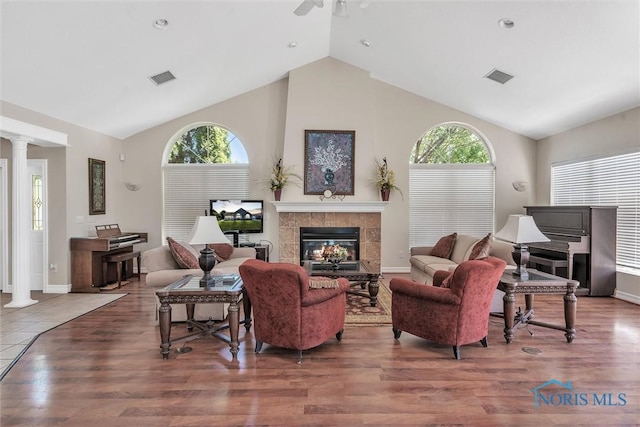 living room with decorative columns, a wealth of natural light, hardwood / wood-style floors, and a fireplace