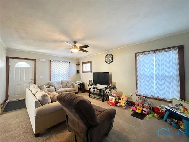 carpeted living room with crown molding and ceiling fan